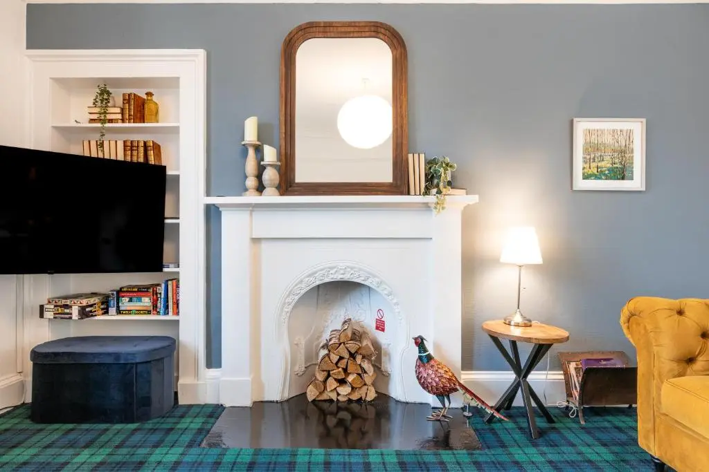 a living room with a fireplace and a mirror at Thistle do Nessly in Inverness