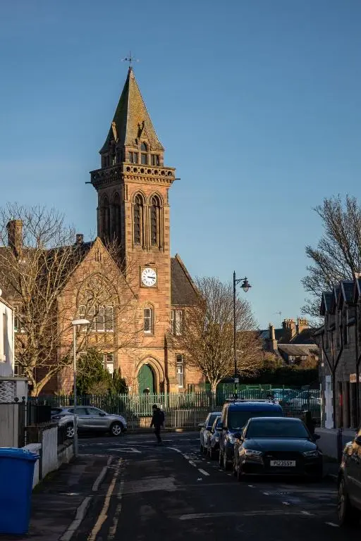 a church with a clock tower and cars parked in front at Hill Street Haven in Inverness