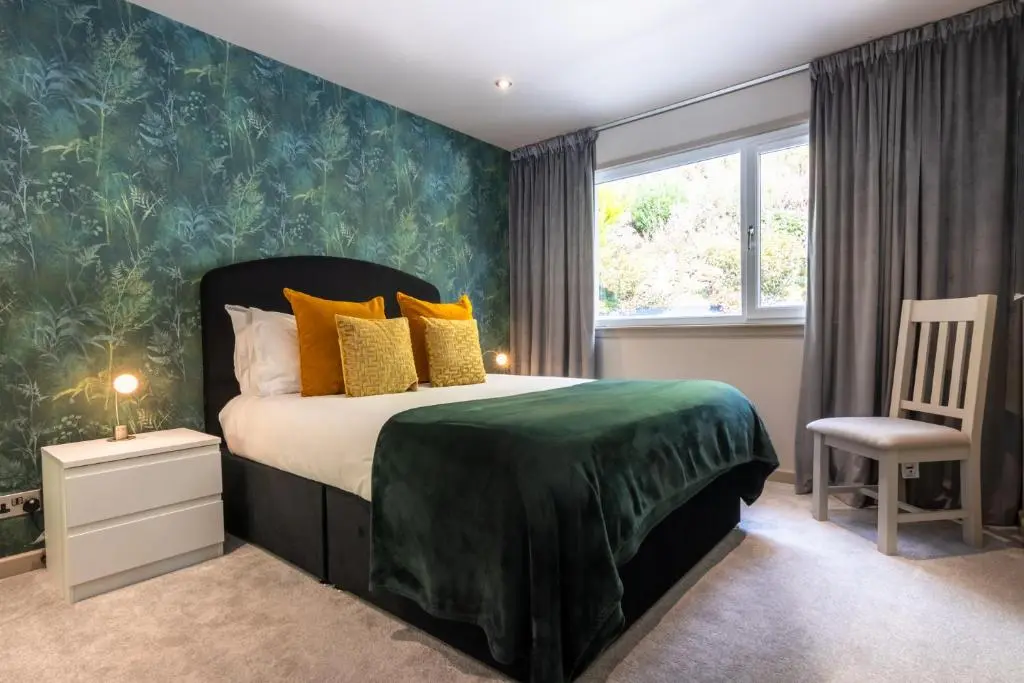 a bedroom with a bed and a chair and a window at Fern View in Inverness