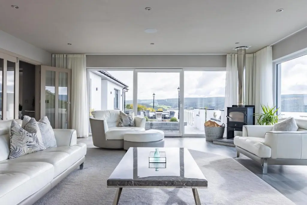 a living room with white furniture and large windows at Fern View in Inverness