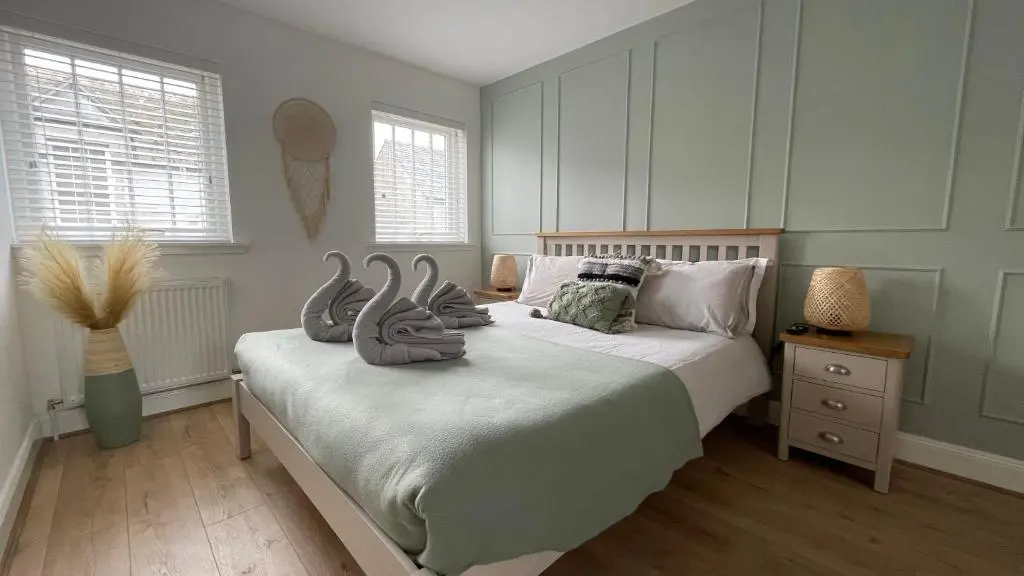 a bedroom with a bed with two swans on it at Harbourside by Caithness Luxury Apartments NC500 - 2 Bedroom holiday home - Sleeps Work teams upto 2 & holiday makers upto 6 with bike store in Wick