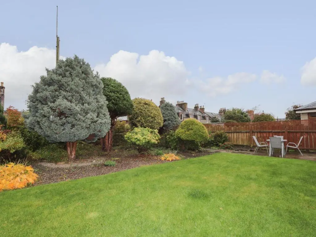 a garden with a lawn and trees and a fence at Tommy's in Inverness