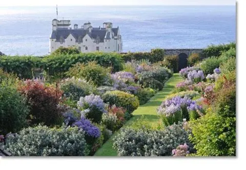 a castle in the middle of a garden with flowers at Dunbeath Coastal Retreat in Dunbeath