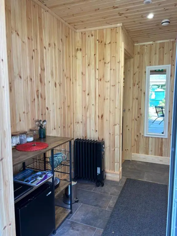 a room with a wooden wall with a stove and a table at Ardenbeg in Grantown on Spey