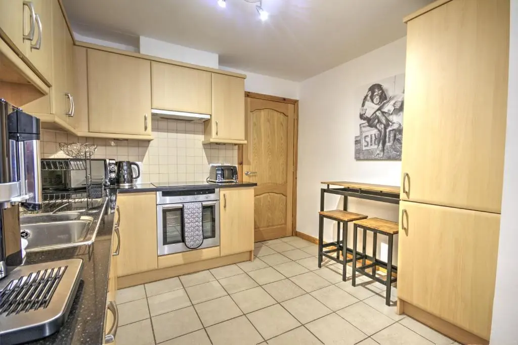 a large kitchen with wooden cabinets and appliances at 5 Argyle Place, Dornoch in Dornoch