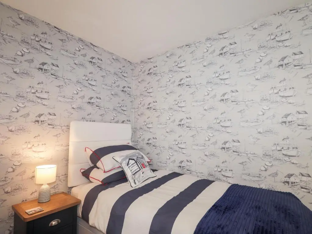 a bedroom with a bed and a wall covered in wallpaper at 2 Seafield Place in Portsoy