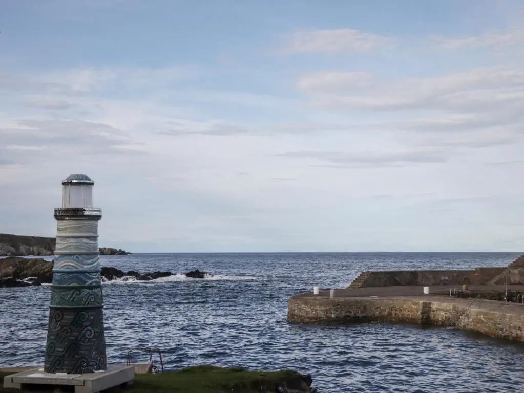 a lighthouse sitting in the water next to the ocean at 2 Seafield Place in Portsoy