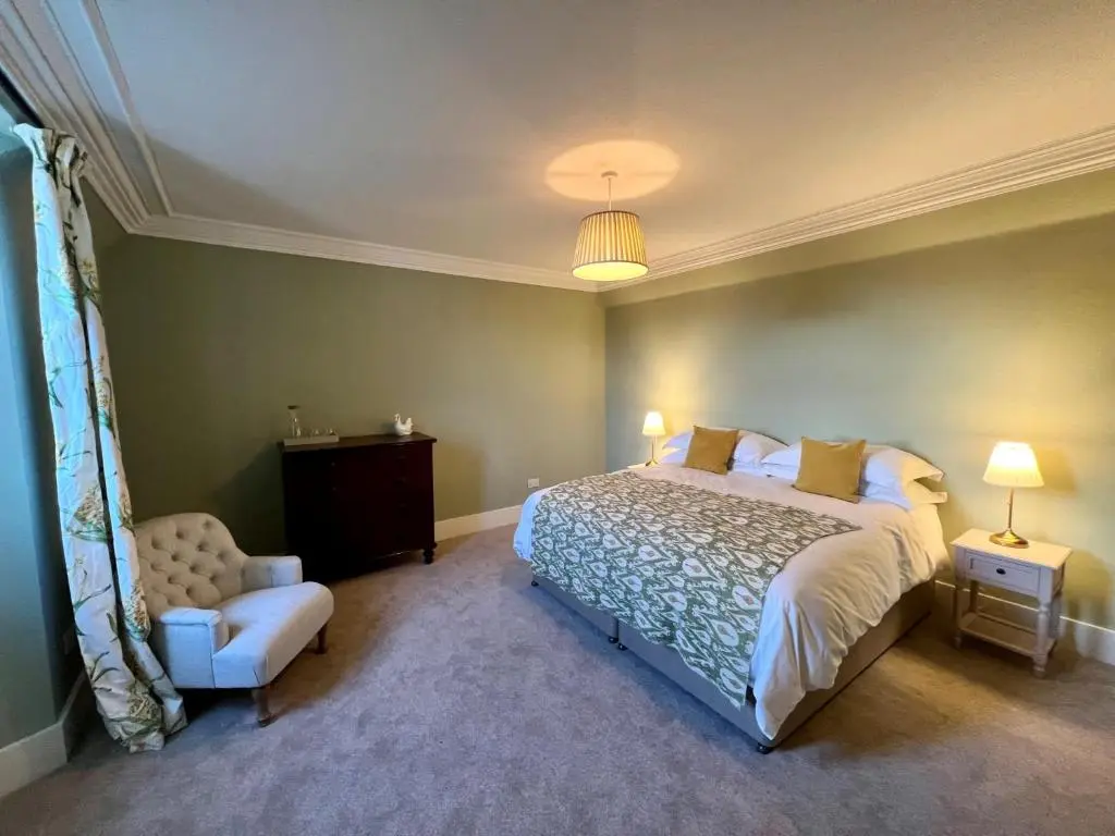 a bedroom with a large bed and a chair at St Marys Farmhouse - Traditional Country Farmhouse with Open Fire in Fochabers