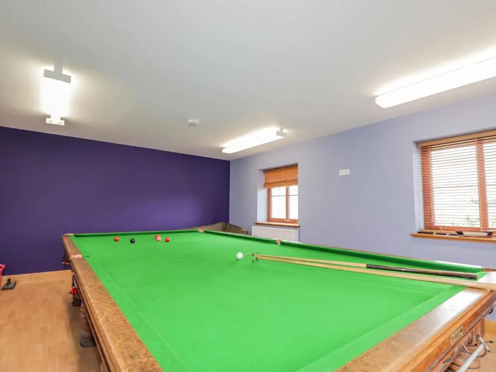 a pool table in a room with purple walls at Lossiemouth Bay Cottage in Lossiemouth