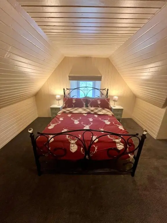 a bedroom with a red bed in a attic at Great Glen Hostel in Spean Bridge