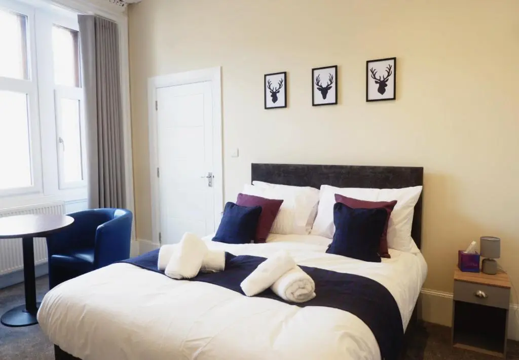 a bedroom with a large bed with blue and white pillows at Jacobite house in Inverness