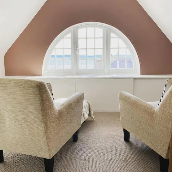an attic room with two chairs and an arched window at Frasers Apartment in Golspie