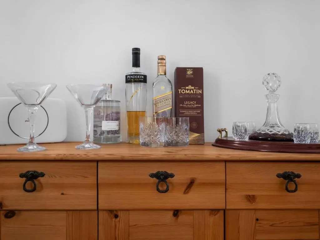 a wooden dresser with wine bottles and glasses on it at Holiday Home Sullivan by Interhome in Drumnadrochit