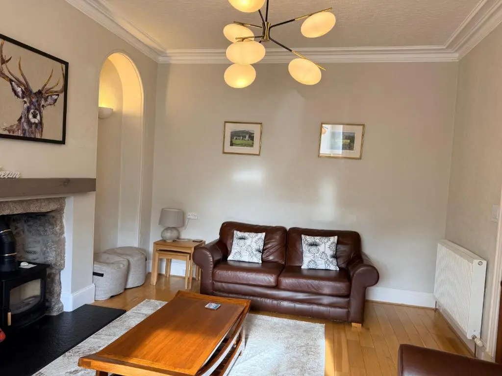 a living room with a leather couch and a table at Spacious 2 Bedroom Flat in heart of Ballater in Ballater