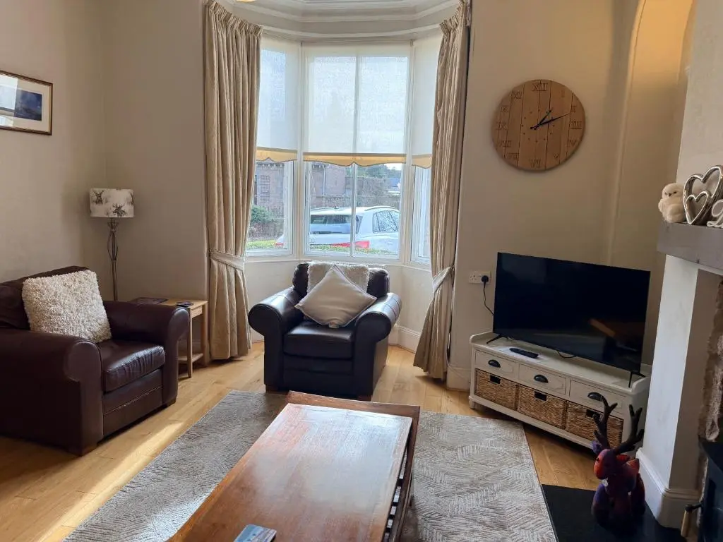 a living room with a couch chairs and a television at Spacious 2 Bedroom Flat in heart of Ballater in Ballater
