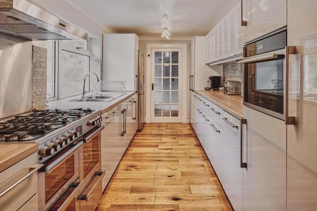 a kitchen with white appliances and a wooden floor at Loch Ness Mansion in Invermoriston