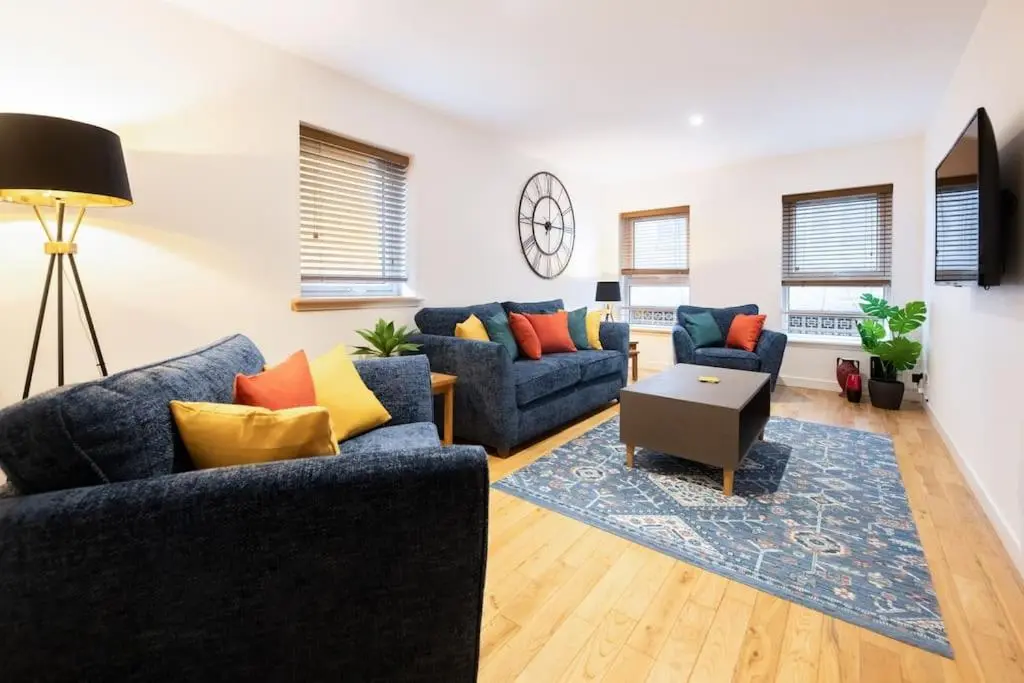 a living room with two blue couches and a table at Modern City Centre Apartment in Inverness in Inverness