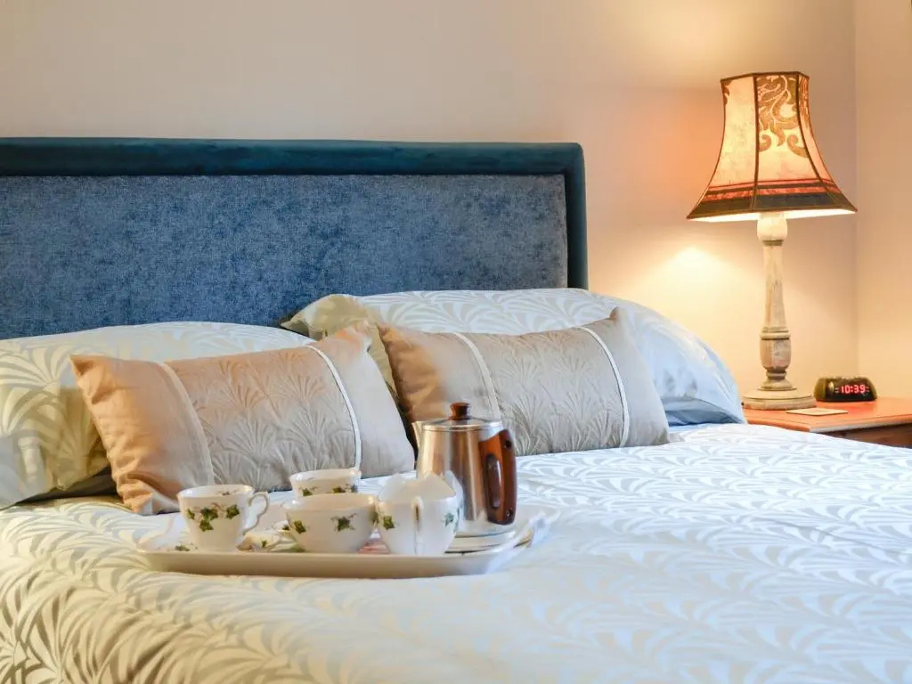 a tray with two tea cups on a bed at Toll Bridge Lodge in Banchory