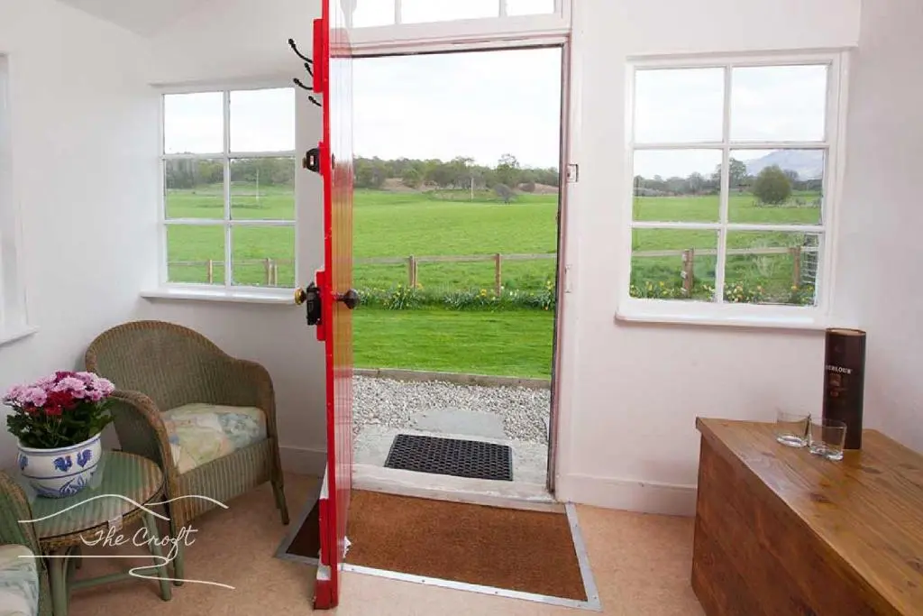 a room with a door with a view of a green field at The Croft Cottage - near Aviemore in Aviemore