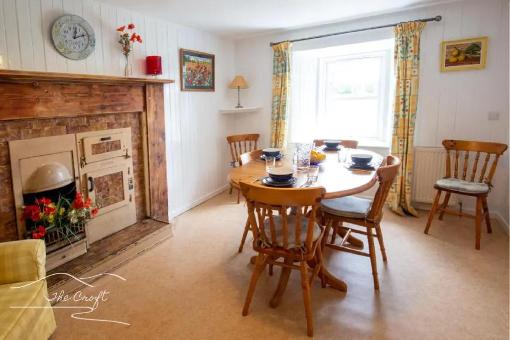 a dining room with a table and a fireplace at The Croft Cottage - near Aviemore in Aviemore