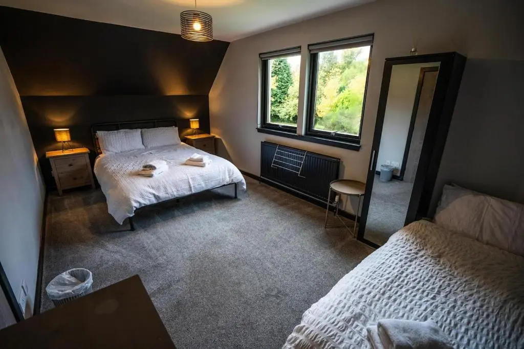a bedroom with two beds and a mirror in it at FAMILY FRIENDLY, HOT TUB, Fire Pit, Spacious & Modern in Fochabers