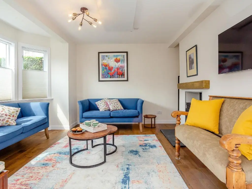 a living room with two blue couches and a table at Woodford - Cottage in Boat of Garten