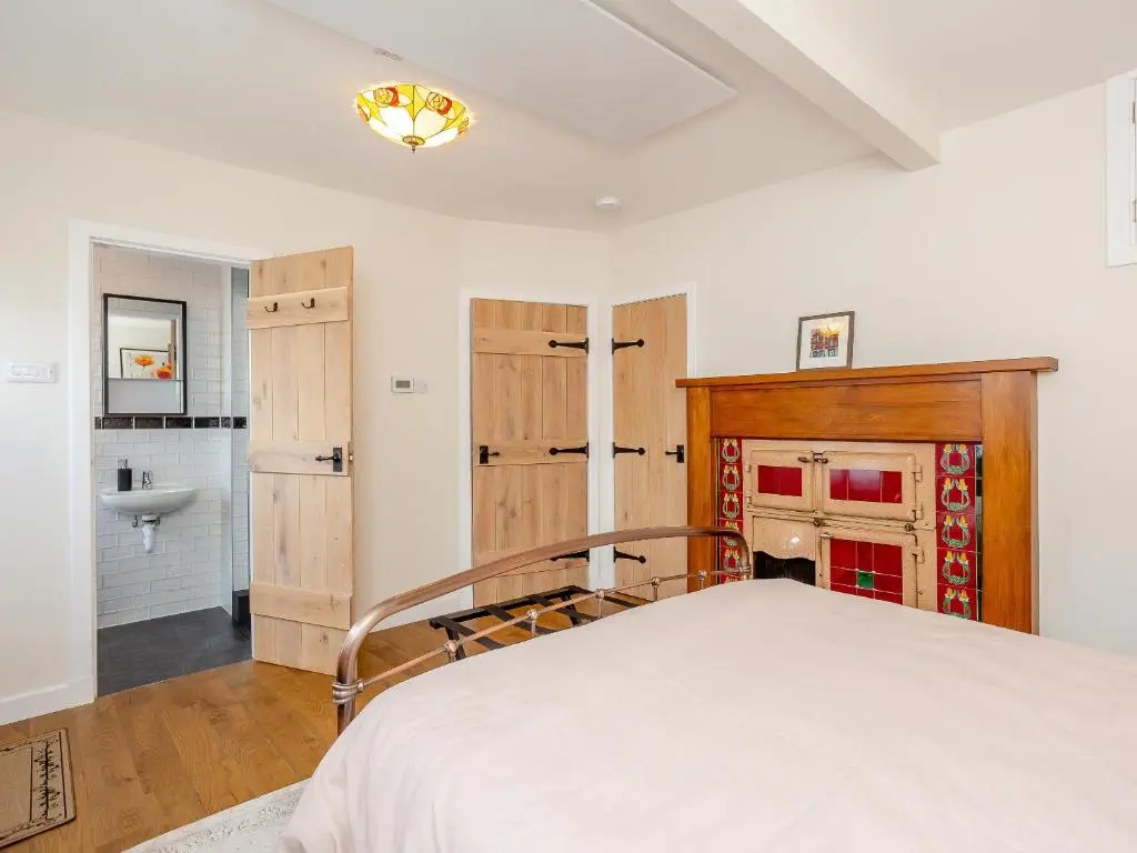 a bedroom with a bed and a bathroom with a sink at Woodford - Cottage in Boat of Garten