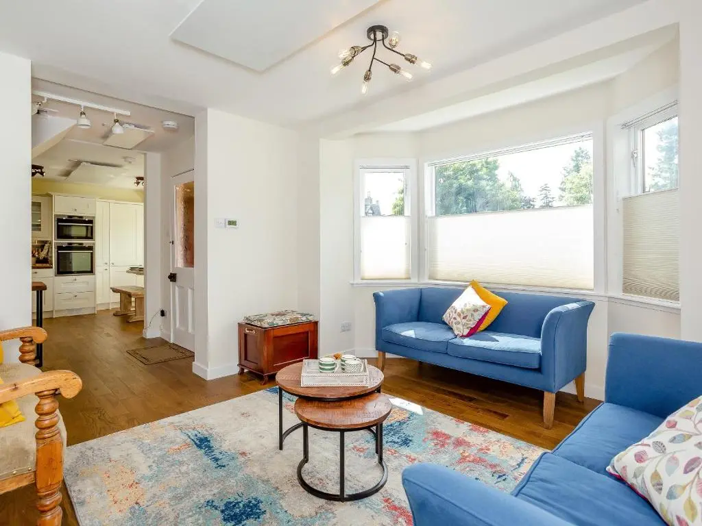 a living room with a blue couch and a table at Woodford - Cottage in Boat of Garten