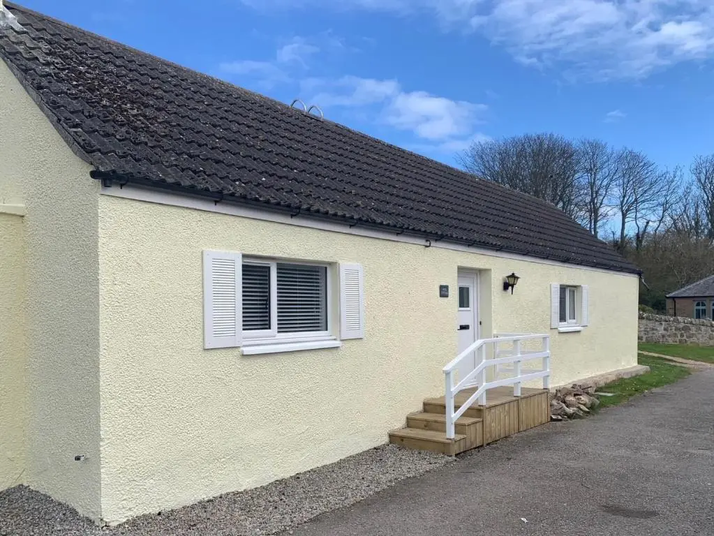 a white house with a white door and stairs at Well Cottages in Portmahomack