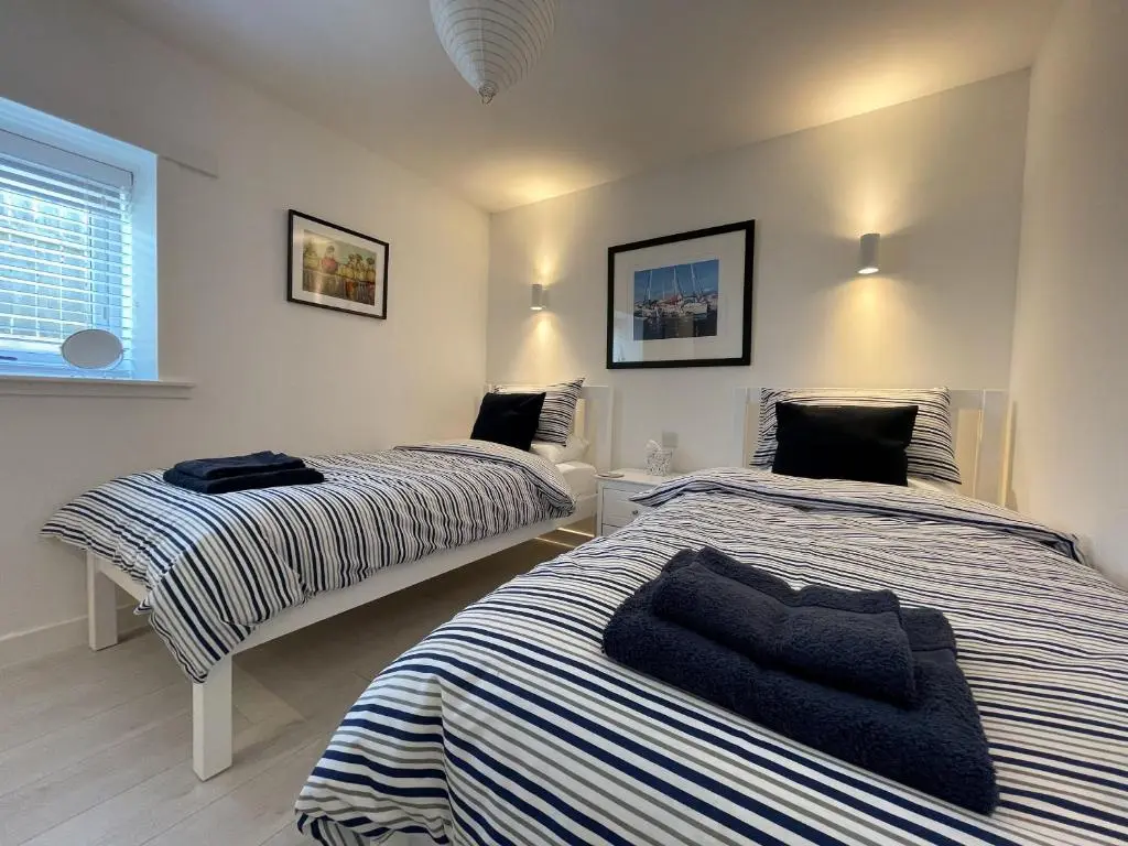a bedroom with two beds and a window at Well Cottages in Portmahomack