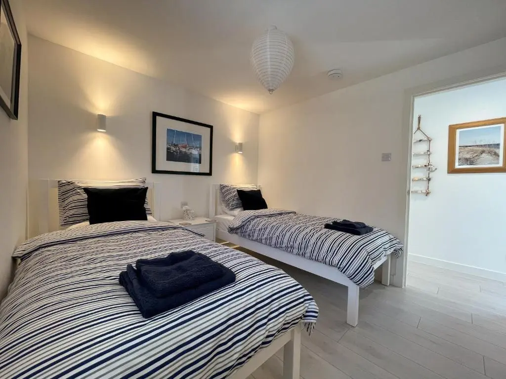 two beds in a white room withskirts at Well Cottages in Portmahomack
