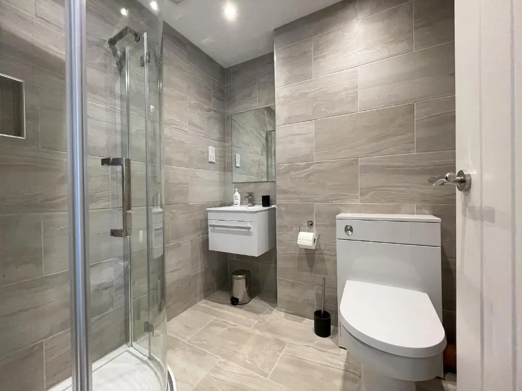 a bathroom with a toilet and a glass shower at Well Cottages in Portmahomack