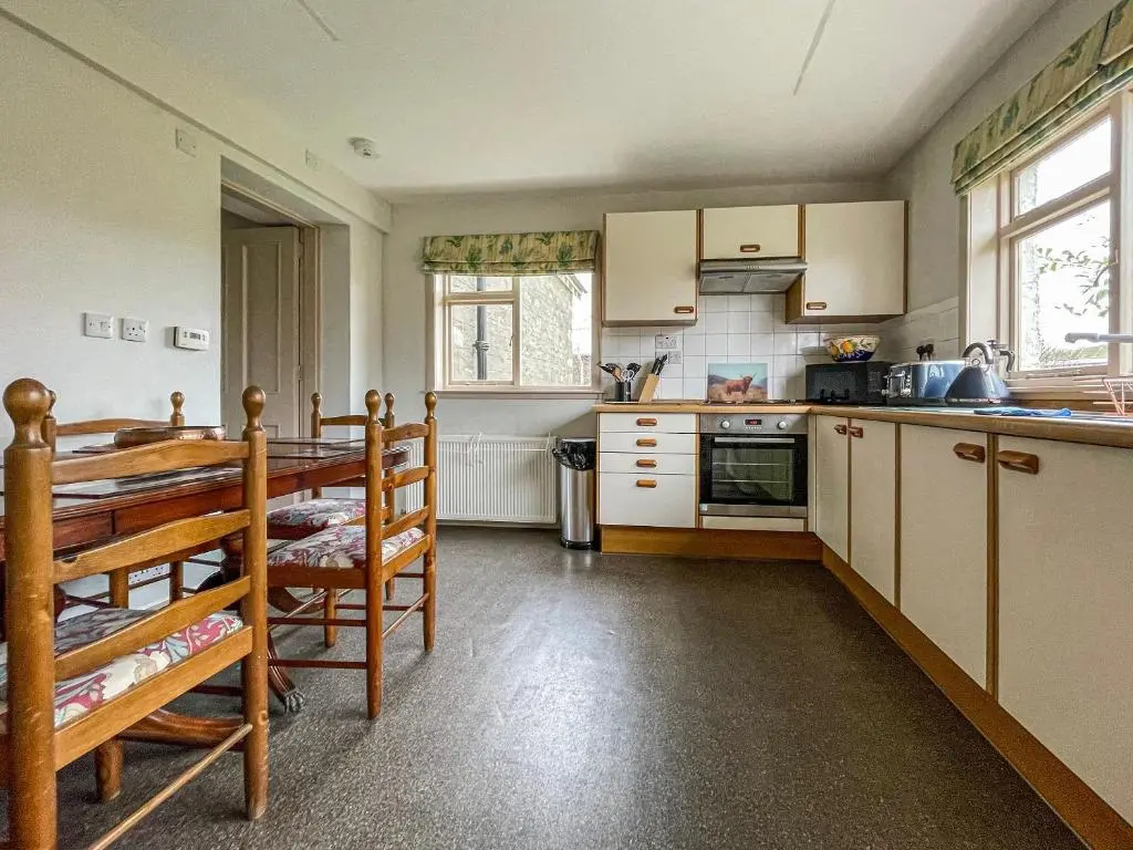 a kitchen with white cabinets and a stove top oven at Milton Cottages in Invercassley