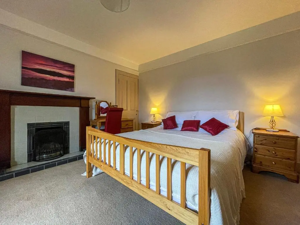 a bedroom with a bed with red pillows and a fireplace at Milton Cottages in Invercassley