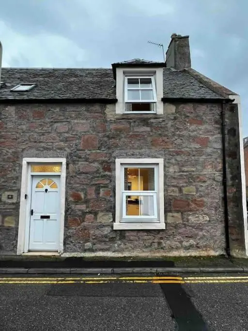 a brick building with two windows and a white door at Central 2 bedroom luxury home close to River Ness in Inverness