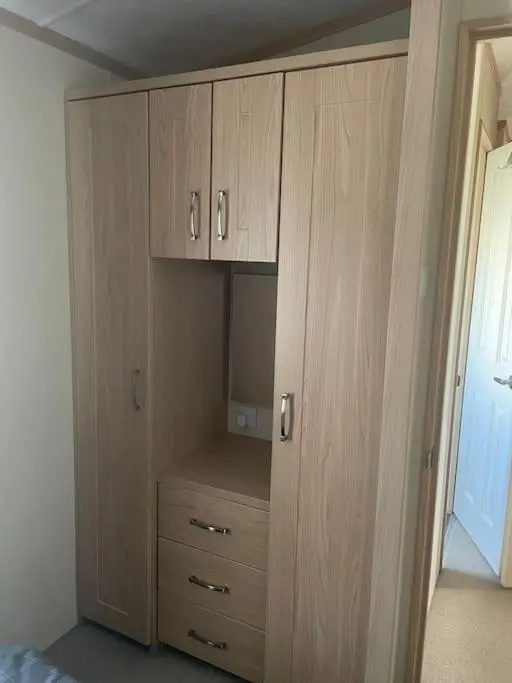 a closet with wooden cabinets in a bedroom at Freedom Lodge-Aviemore with FREE Starlink Superfast broadband 150mbps - All bedding and towels included - Pet Free in Aviemore