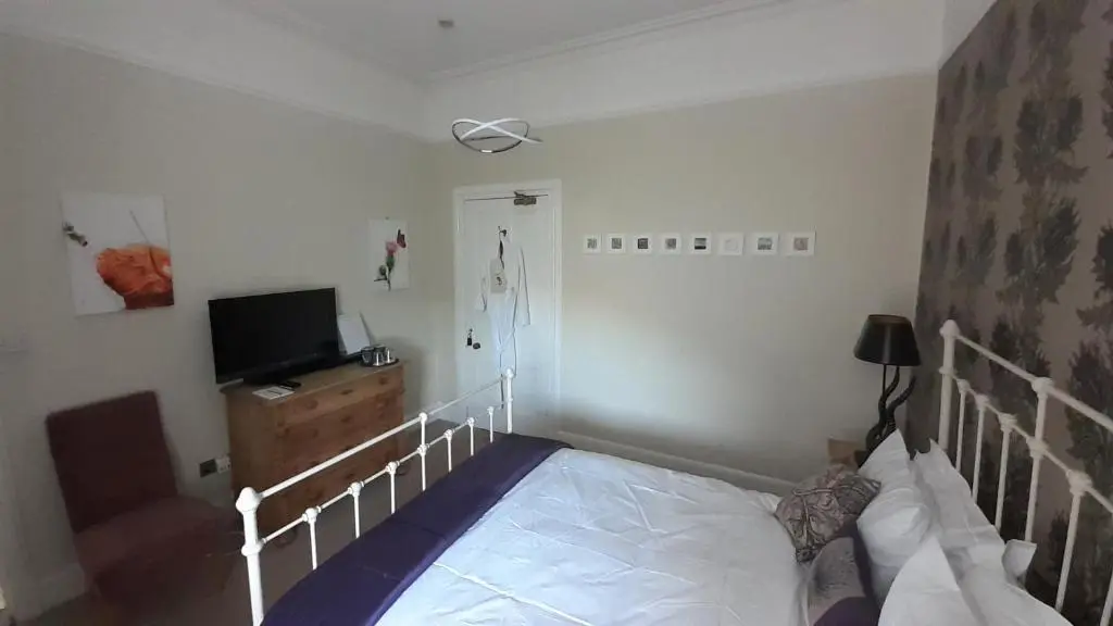 a bedroom with a bed and a flat screen tv at Trafford Bank Guest House in South Kessock