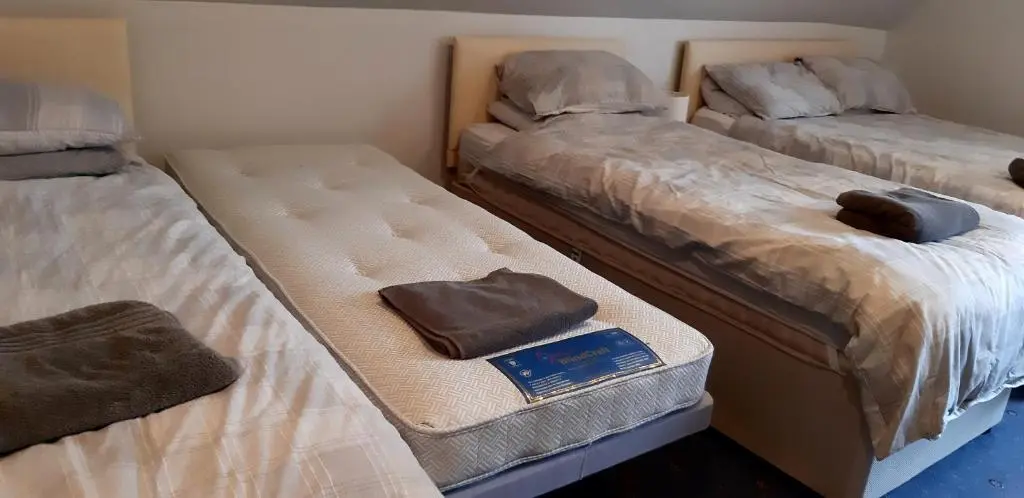 a room with three beds with a book on it at 1 Bed Flat - Sleeps 4 - Garden - Parking - Wifi in Inverness