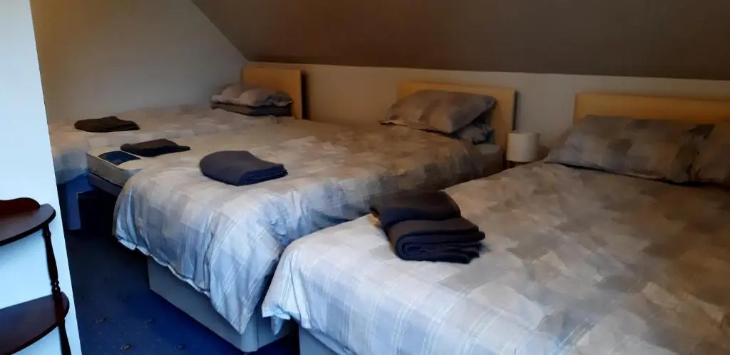 a room with three beds with blue pillows on them at 1 Bed Flat - Sleeps 4 - Garden - Parking - Wifi in Inverness