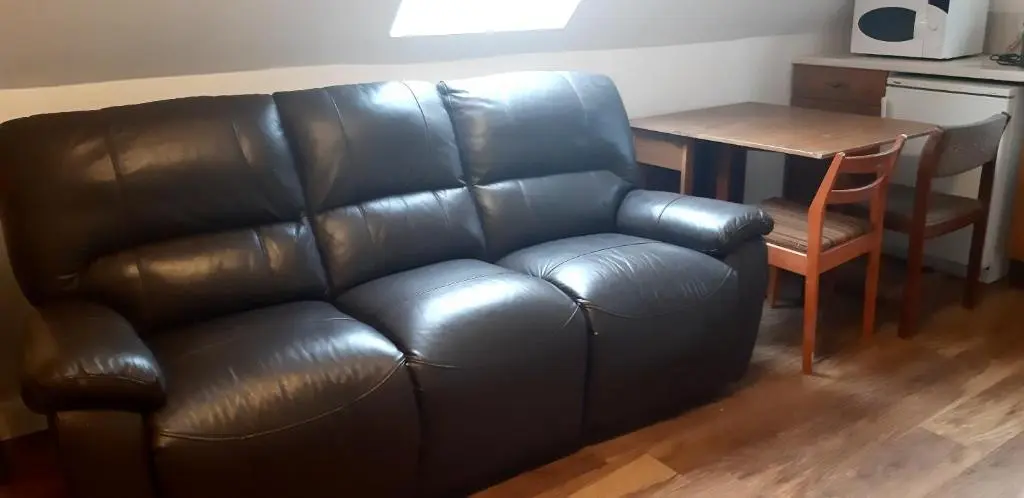 a leather couch in a living room with a table at 1 Bed Flat - Sleeps 4 - Garden - Parking - Wifi in Inverness