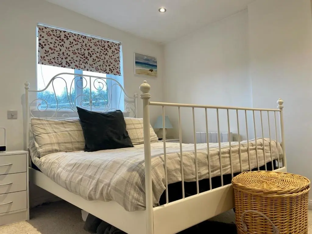 a bedroom with a white bed and a window at Woodside Cabin in Inverness