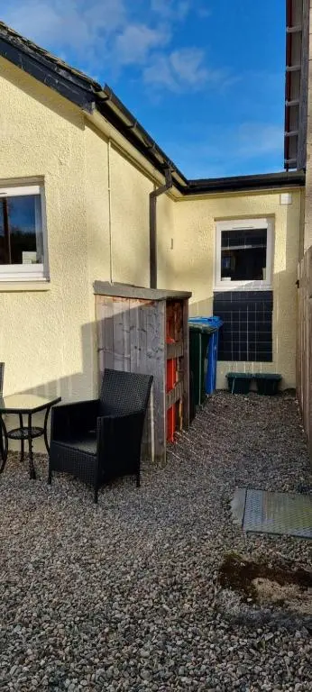 a patio with a bench and a table and a building at The Shelter Stone Cottage in Aviemore