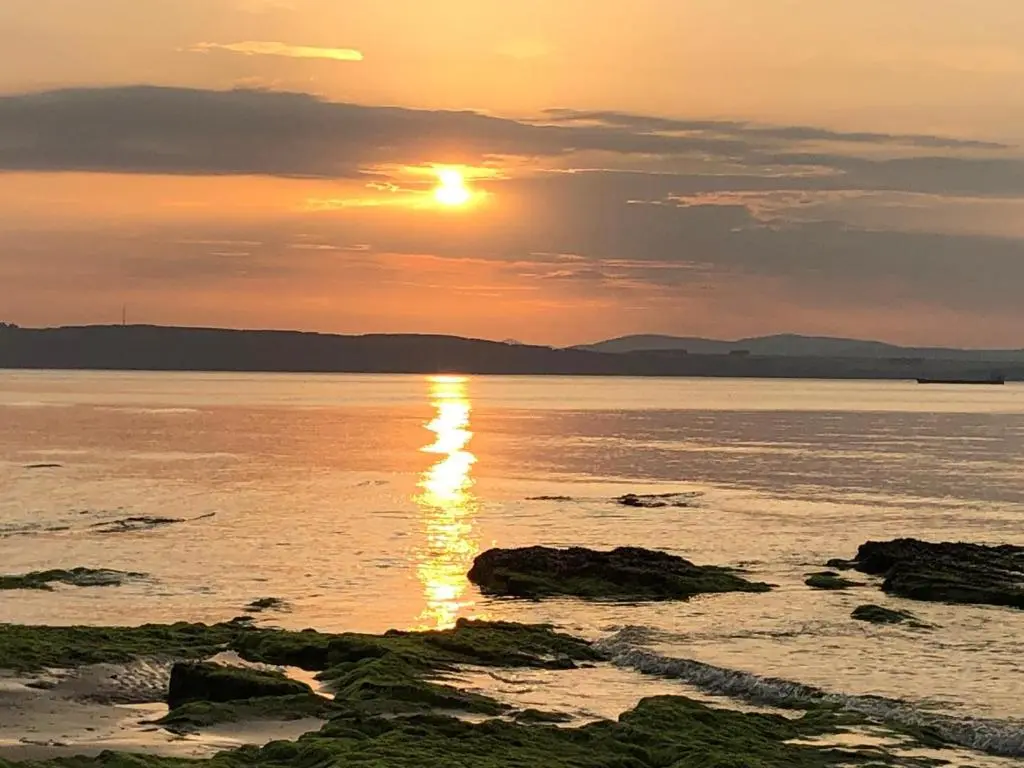 a sunset over a body of water with rocks at Corsee House in Nairn
