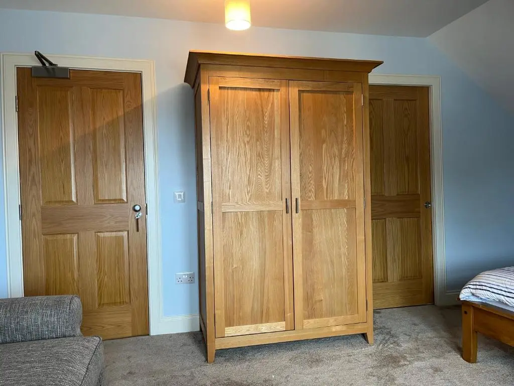 a bedroom with wooden cabinets next to a bed at Corsee House in Nairn