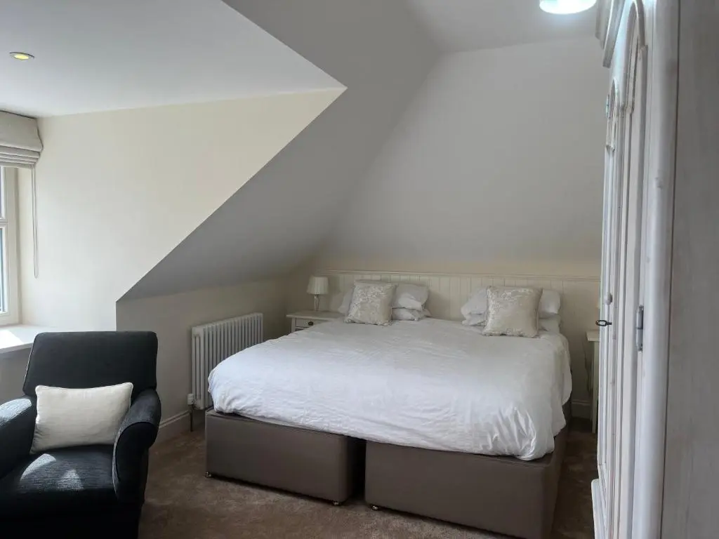a bedroom with a white bed and a chair at Corsee House in Nairn