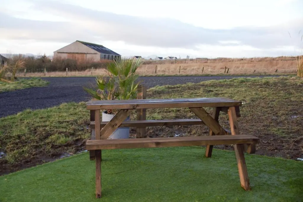 a wooden bench sitting on the grass near a field at The Windy Roost in Occumster