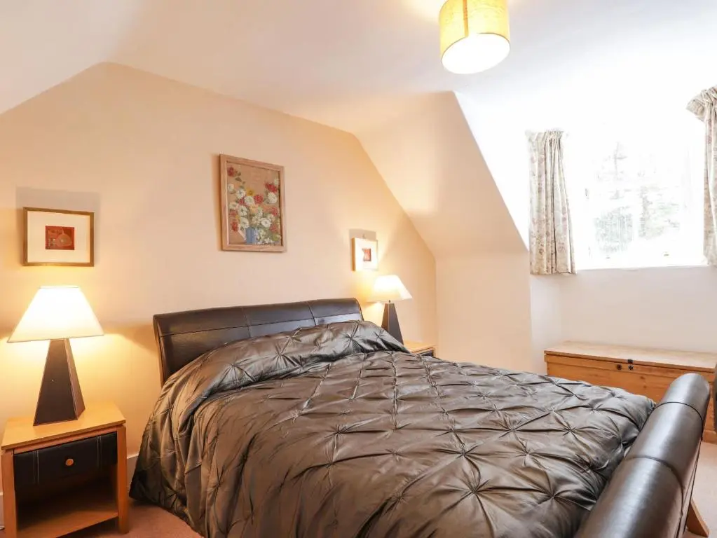 a bedroom with a bed and two lamps and a window at The Larches in Kingussie
