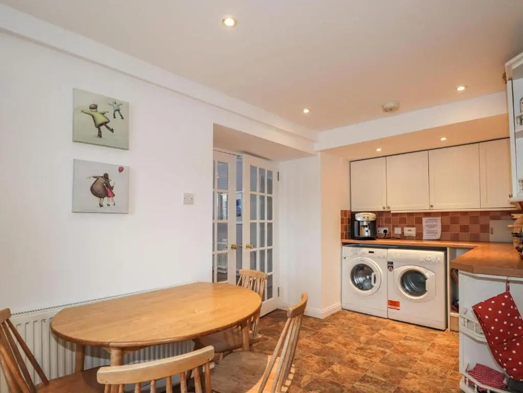 a kitchen and dining room with a table and a washing machine at The Larches in Kingussie
