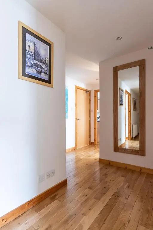a living room with a mirror and wooden floors at The Rooftops Reservation in Inverness