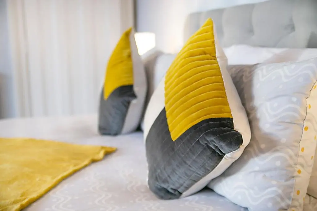 three pillows on a bed with yellow and white at Constancevilla B9 - Grampian Lettings Ltd in Aberdeen